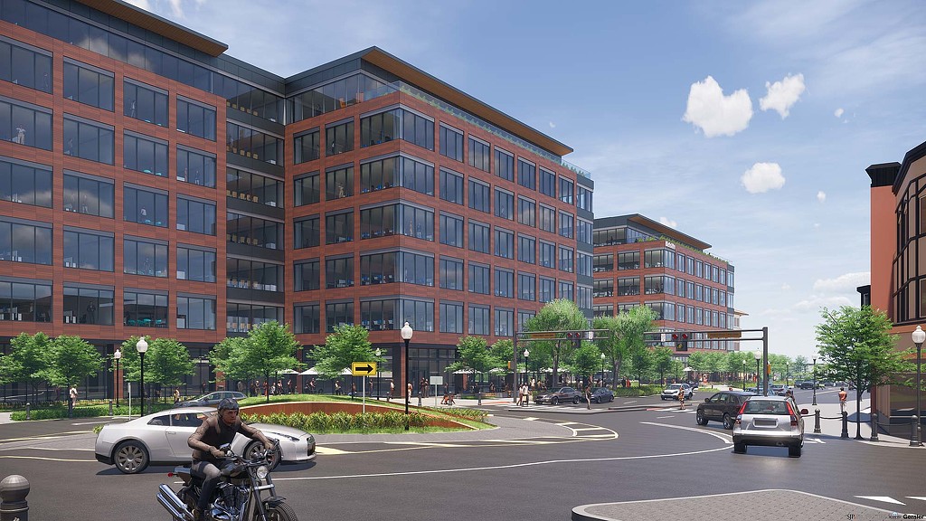 A person riding a motorcycle on a street in front of a large building.